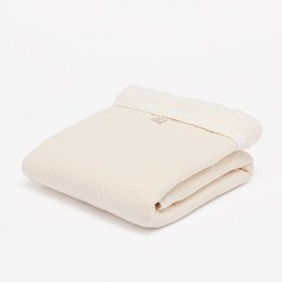Soft, off-white cot blanket with a dotted pattern, perfect for keeping babies warm and cozy.