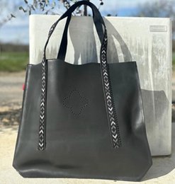  Black leather tote bag with decorative stitching on the straps.
