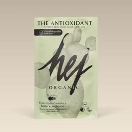 Antioxidant face mask with organic ingredients. Green and white packaging. Woman applying face mask.