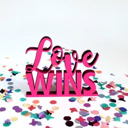 A colorful, vibrant statue with the text "Love Wins" in bold, pink letters. The statue is surrounded by confetti-like shapes in various bright colors, creating a celebratory and joyful atmosphere.