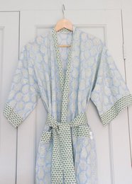  A long, lightweight dressing gown in a soft blue and white floral print with a contrasting green and white polka dot pattern on the trim and belt.