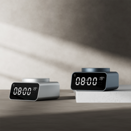 Sleek, modern alarm clock in silver and black colors with digital display showing time and temperature.