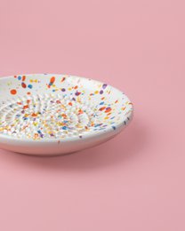 Handmade ceramic plate grater with a multicolor carnival design. Features a round shape and vibrant colors including orange, yellow, and blue.