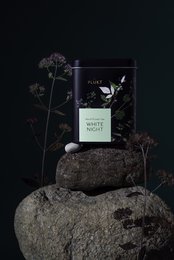 White Night tea blend in a black and green package, featuring a floral design and a transparent window to view the tea leaves.