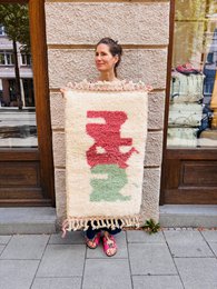 Handwoven Berber carpet with red and green geometric pattern, cream wool base, traditional design.