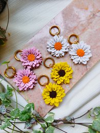 "Colorful flower statement earrings in pink, white, yellow. Daisy design with gold-tone metal accents."