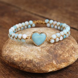 This HEART Amazonite Bracelet features a heart-shaped amazonite stone set in a gold-tone metal frame, surrounded by white and light blue beads. The bracelet has a delicate, feminine style.