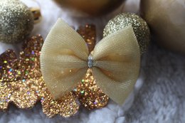 A gold and glittery hair clip with a tulle bow, suitable for children's hair accessories.