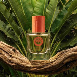  'WAKA - MADAGASCAR Eau de Parfum is a perfume product. The product has a red cylindrical bottle with a silver cap. The bottle is surrounded by colorful floral patterns and textures, suggesting a tropical or nature-inspired design.'