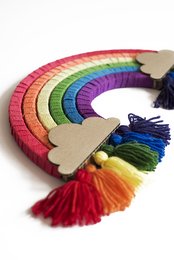 Colorful rainbow-shaped DIY craft kit with tassels and wooden accents. Includes a variety of vibrant rainbow hues and textured materials for a unique handmade decoration or wall hanging.
