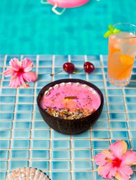  Tropical scented candle with coconut, passion, raspberry, and hibiscus shell. Vibrant orange, pink, and white floral accents.