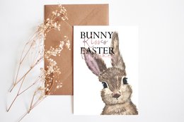 Postcard with a realistic illustration of a bunny, featuring the text "Bunny Easter" on a beige background with floral accents. The postcard is available with or without an envelope.
