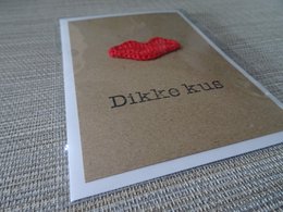 Handmade greeting card with a red heart-shaped design and the text "Dikke kus" (Dutch for "Big kiss") on a kraft paper background.