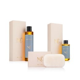 Luxury beauty gift set with golden amber bottles, blue labels, cream packaging, soap bar, and skincare products.