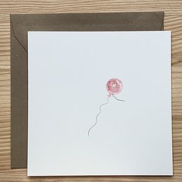 A pink balloon-shaped card with a simple, minimalist design. The card appears to be part of a baby or children's product line.