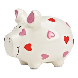 A ceramic piggy bank in the shape of a pig, with a white body and pink and red heart-shaped patterns. The piggy bank is a decorative storage item for holding coins or other small items.