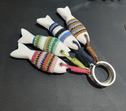 Colorful, striped fish-shaped keychains made of wood and wrapped in yarn.