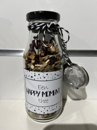 A glass jar filled with various tea leaves and a "Happy Moment" label. The jar has a black lid and appears to be a decorative or gift-packaged tea product.