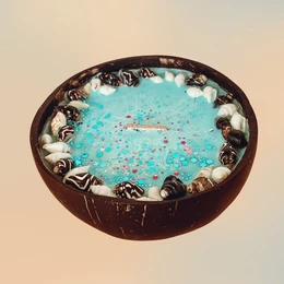 Oval-shaped scented candle with seashell and tiare flower design, featuring a turquoise blue wax with floral accents.