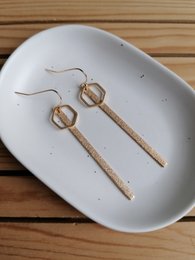 Gold statement earrings with a minimalist, modern design. Features a simple, elongated oval shape with a sleek, polished finish.