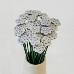 A bouquet of artificial forget-me-not flowers in various shades of blue, purple, and white. The flowers have a round, daisy-like shape and are arranged in a vase.