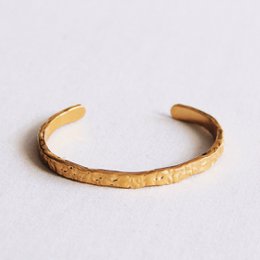 Gold-toned bangle bracelet with a textured, hammered finish.