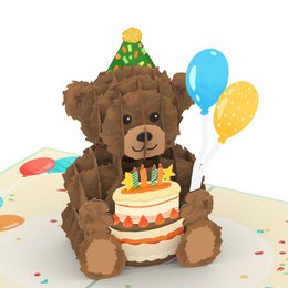 A plush brown teddy bear holding a birthday cake with colorful balloons in a pop-up birthday card.