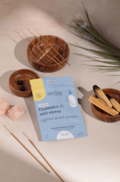 Sugar-free anti-stress gummies in a bottle, with a wooden candle holder and a book on the side.
