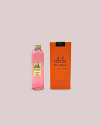 Magenta-colored reed diffuser with a label featuring a vintage-style design. The diffuser appears to be made of glass and contains a liquid fragrance.