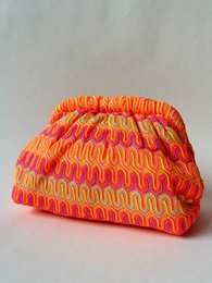  Colorful knitted brooch bag with sunset swirl pattern in orange, pink, red, purple. Textured geometric design.