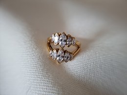 Elegant gold-toned statement ring with clustered clear stones, suitable for formal or casual wear.
