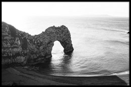 Dramatic black and white landscape poster featuring the iconic Durdle Door rock formation in Dorset, England. Available in a variety of sizes to suit any space.