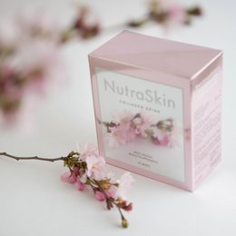 NutraSkin Collagen Drink is a pink-colored liquid supplement packaged in a pink box with floral accents. The product appears to be a collagen-based drink mix.