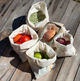 Set of 4 organic cotton bulk bags for shopping, featuring various produce items such as vegetables and fruits. The bags have a natural, earthy aesthetic with printed designs of leaves and other botanical elements.