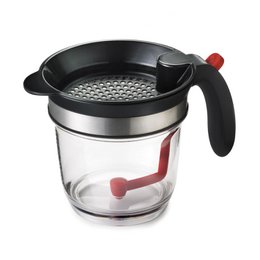 "Clear glass fat separator with black lid, stainless steel band, red handle and spout for gravy"