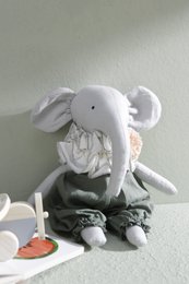 Soft, plush rag doll in the shape of an elephant with gray fabric and green accents. Suitable for children as a cuddly toy.