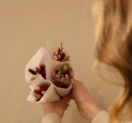 Dried flower bouquet with small red and white flowers, wrapped in white paper.