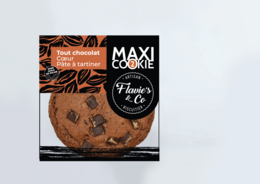 A large, round chocolate cookie with heart-shaped chocolate spread on top. The cookie has a dark, rich chocolate color and appears to be soft and chewy in texture.