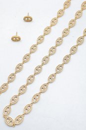 Ensemble assorti comprenant un collier, un bracelet en chaîne et une paire de boucles d'oreilles puces. Chaque bijou est composé d'une succession de maillons en forme de maille marine entièrement pavés de petits strass scintillants.