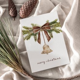 Merry Christmas card with gold bell, green pine branches, brown ribbon bow, festive holiday greeting.