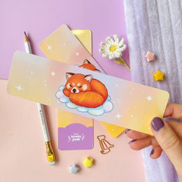 Colorful laminated bookmark featuring a whimsical illustration of a cat astronaut in a starry galaxy background.
