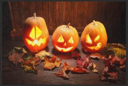 Halloween-themed doormat with carved pumpkins and autumn leaves.