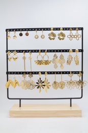 Lot de 15 paires de boucles d'oreilles assorties en acier inoxydable, présentées sur un présentoir métallique avec socle en bois.