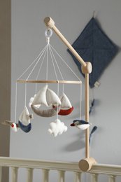 A wooden mobile with hanging white and blue fabric shapes, designed for a baby's nursery.