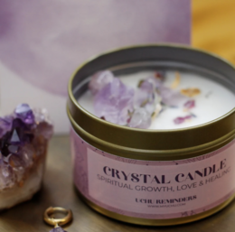 A round, tall crystal candle with a purple and white color scheme. The candle is contained in a gold-colored tin with the label "Crystal Candle" printed on it.