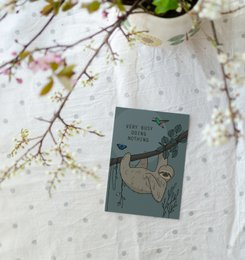 Postcard featuring a sloth design, suitable for Christmas cards. The postcard has a whimsical illustration of a sloth hanging from a branch with pink flowers.