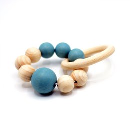 A wooden baby rattle with beads in various shades of blue and natural wood tones. The rattle has a simple, minimalist design and is suitable for infants and toddlers.