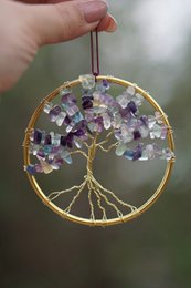 Amethyst crystal tree of life pendant in gold-colored frame. Vibrant purple and white crystals arranged in a circular shape.