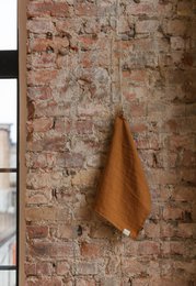 Cinnamon-colored linen kitchen towel with a textured, natural appearance. Suitable for use in the kitchen or as a decorative accent.