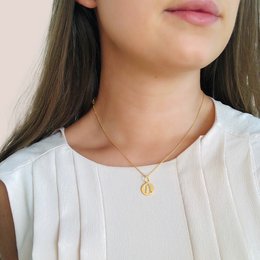 Gold-toned pendant necklace with a circular charm featuring a silhouette design.